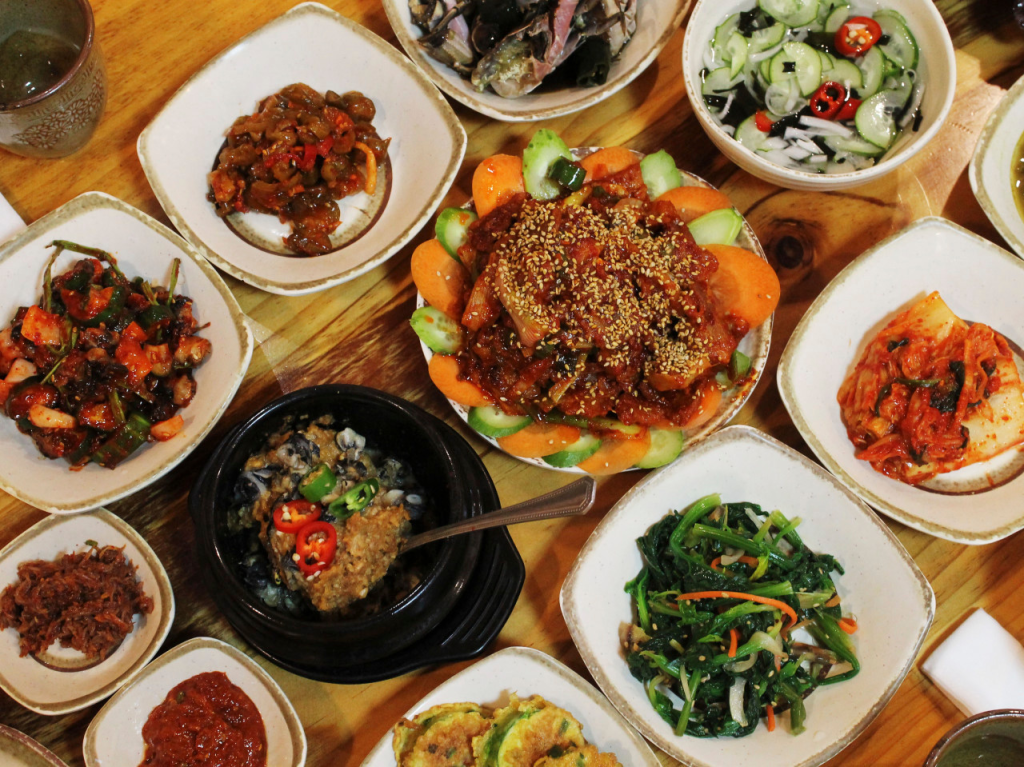 多様な韓国料理が盛り付けられたテーブル。仲間と楽しむ美味しい食事が並んでいる。